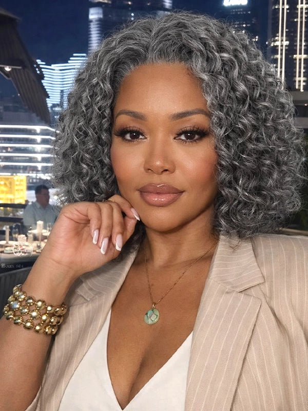 Front view of a medium-length salt and pepper gray wig with loose water wave curls, worn by a real model in a night city scene, made of 100% human hair, ideal for natural, elegant everyday or evening styling
