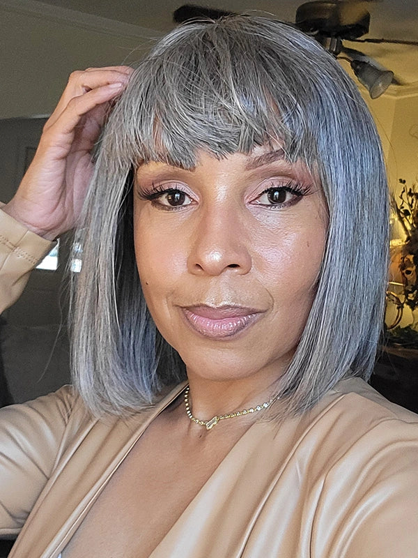 A middle-aged woman wearing the Salt and Pepper wig, ideal for women over 40 seeking elegance and maturity. Perfect for formal events, dinners, or professional settings, with chic bangs and a small lace front