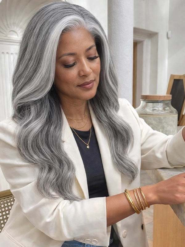 Side view of a long silver grey salt and pepper wavy wig with signature white front streaks, worn by a real model, made of 100% human hair, perfect for natural and elegant everyday styling