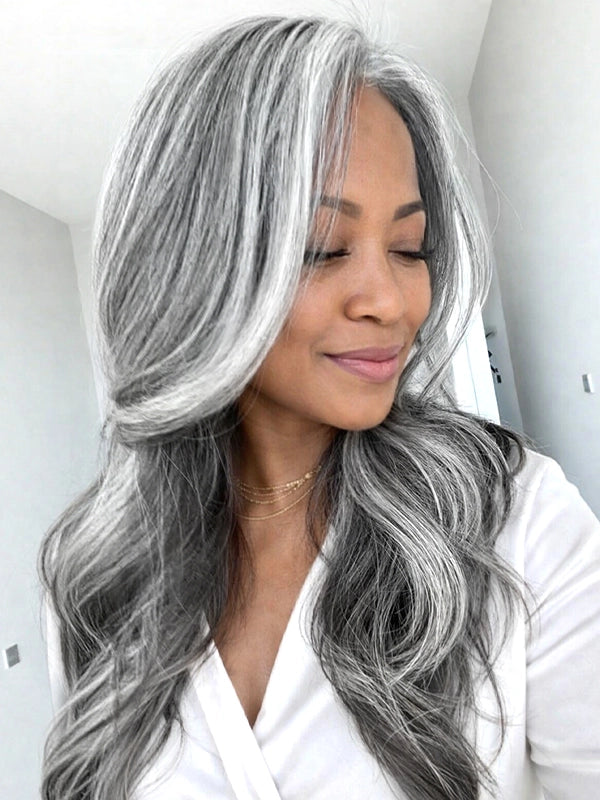 Side view of a long silver grey salt and pepper wavy wig with signature white front streaks, worn by a real model, made of 100% human hair, perfect for natural and elegant everyday styling